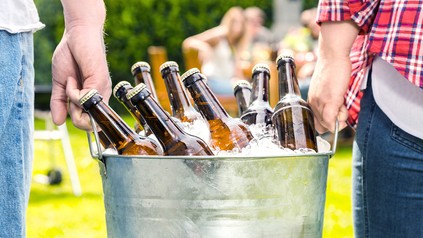 Ein Eiskübel mit Bierflaschen. Der Kübel wird von zwei männlichen Händen gehalten.