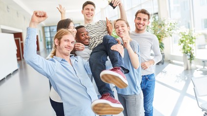 Eine Gruppe von Erstsemestern trifft sich freudig im Flur der Universität.