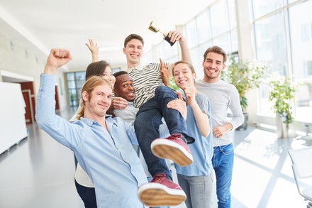 Eine Gruppe von Erstsemestern trifft sich freudig im Flur der Universität.
