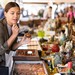 Junge Frau stöbert auf einem Flohmarkt zwischen Vintage-Deko, Schmuck und kleinen Trödelstücken.