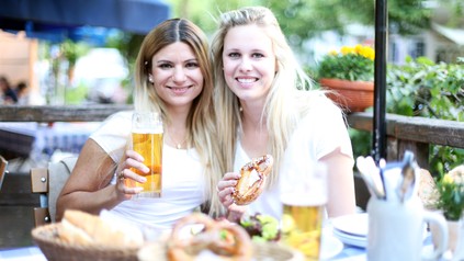 Zwei Studierende sitzen in einem Münchner Biergarten und genießen eine Brotzeit.