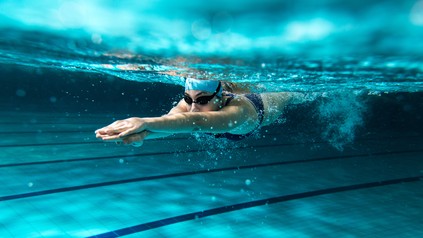 Schwimmerin zieht unter Wasser eine Bahn in einem Schwimmbecken.