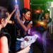Junge Erwachsene spielen Lasertag in einer dunklen Indoor-Arena und zielen mit leuchtenden Laserpistolen.
