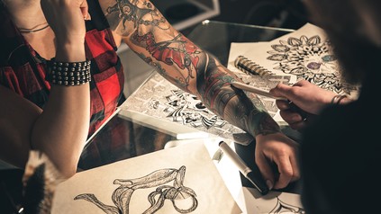 Tattoo-Artist bei der Arbeit an einem Tattoo bei einer Kundin.