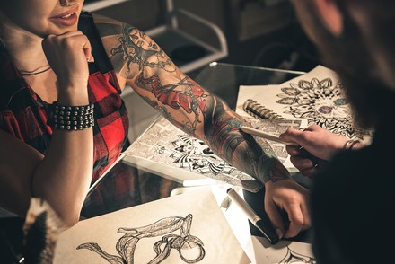 Tattoo-Artist bei der Arbeit an einem Tattoo bei einer Kundin.
