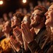 Alttext: Junge Zuschauer applaudieren begeistert während einer Theateraufführung in München.