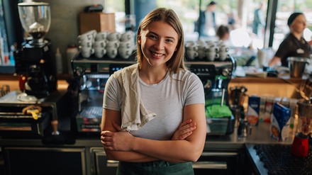 Barrista steht vor einer großen Kaffeemaschine in einem Cafe.