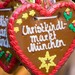 Lebkuchenherz mit der Aufschrift „Christkindl Markt München“ vor weiteren Weihnachtsmarkt-Lebkuchen.