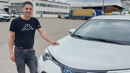Junger Mann steht vor weißem Auto.