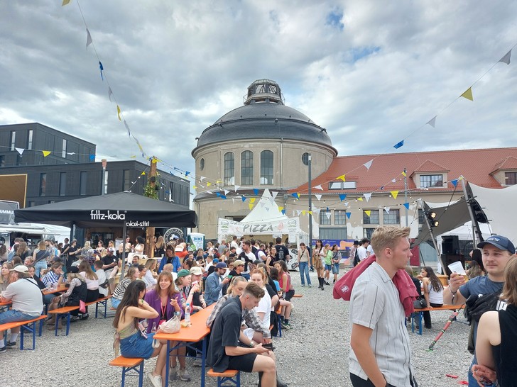 Menschen sitzen auf Bierbänknen.
