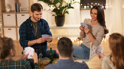Junge Menschen spielen Karten und trinken Bier.