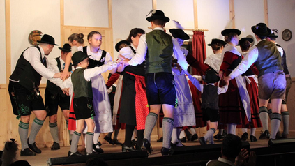 Gruppe aus jungen und alten Leuten beim bayerischen Volkstanz.