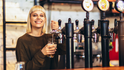 Junge Frau zapt Bier.