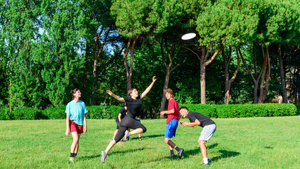 Gruppe aus jungen Leuten spielt Frisbee im Park.