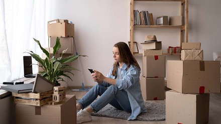 WG, Wohnung, Wohnheim - was passt am besten zu dir? (Foto: © stock.adobe.com/mtrlin) Studentin zwischen Umzungskartons