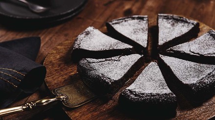 Auch diesen Dessert-Klassiker kannst du leicht auch in vegan backen. (Foto: © stock.adobe.com/trendyrowdy) Schokokuchen mit Puderzucker auf Brett.