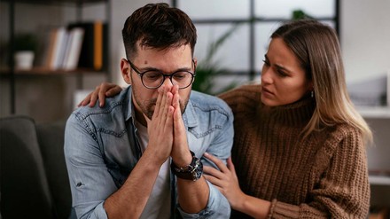 Beistand hilft so ziemlich in jeder Lebenslage. (Foto: © stock.adobe.com/JustLife) Trauriger Mann mit Frau auf dem Sofa; sie tröstet ihn.