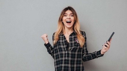 Finanzielle Sorgen? – Lass dir helfen. (Foto: © stock.adobe.com/Drobot Dean) Junge Frau in Karohemd, die sich freut.