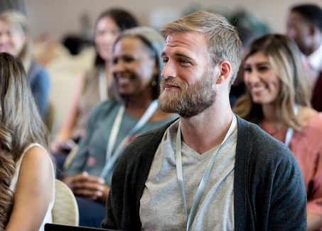 Mann mit Bart sitzt in einer Zuschauergruppe