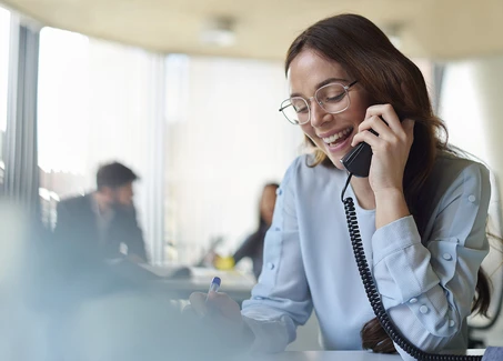Frau mit blauer Bluse und Telefon in der Hand