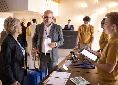 Studentin am Empfang einer Veranstaltung mit zwei Gästen