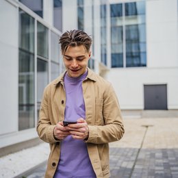 Ein Mann vor einem Bürogebäude mit Smartphone