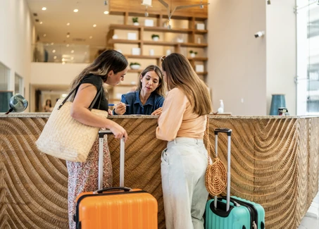 Empfangsmitarbeiterin an einem Hoteltresen mit zwei Gästinnen
