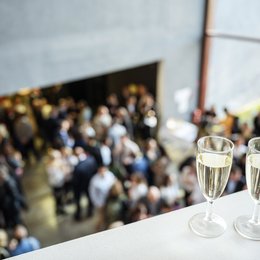 Zwei Sektgläser und eine große Menschenmenge im Hintergrund