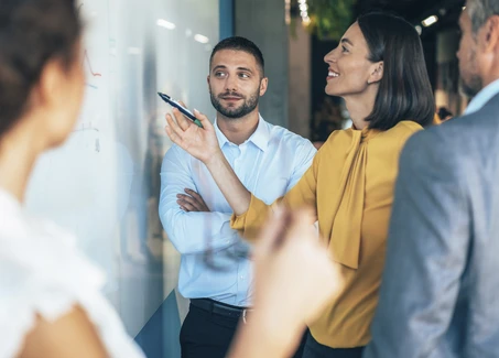 Vier Personen stehen vor einem Whiteboard
